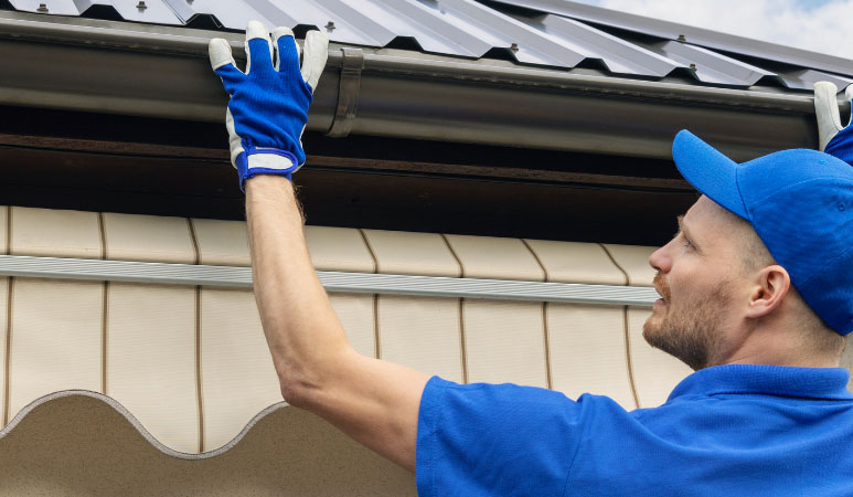 Man installing metal gutters on the roof