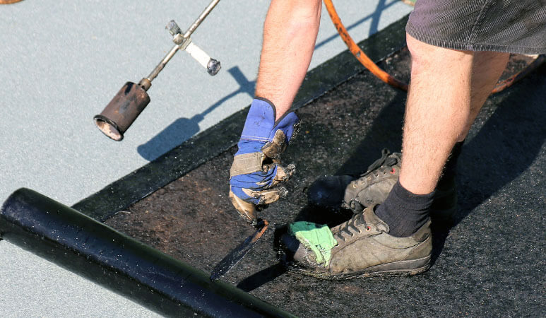 Installer placing and burning the tar on a roof install.