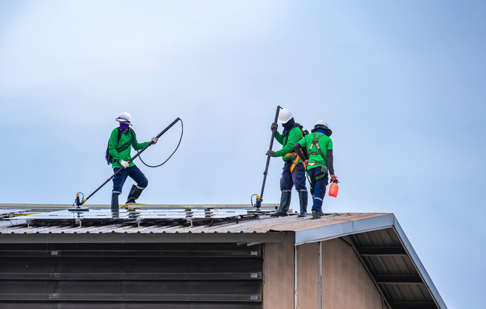 Professional roof cleaning service workers clean the building roof